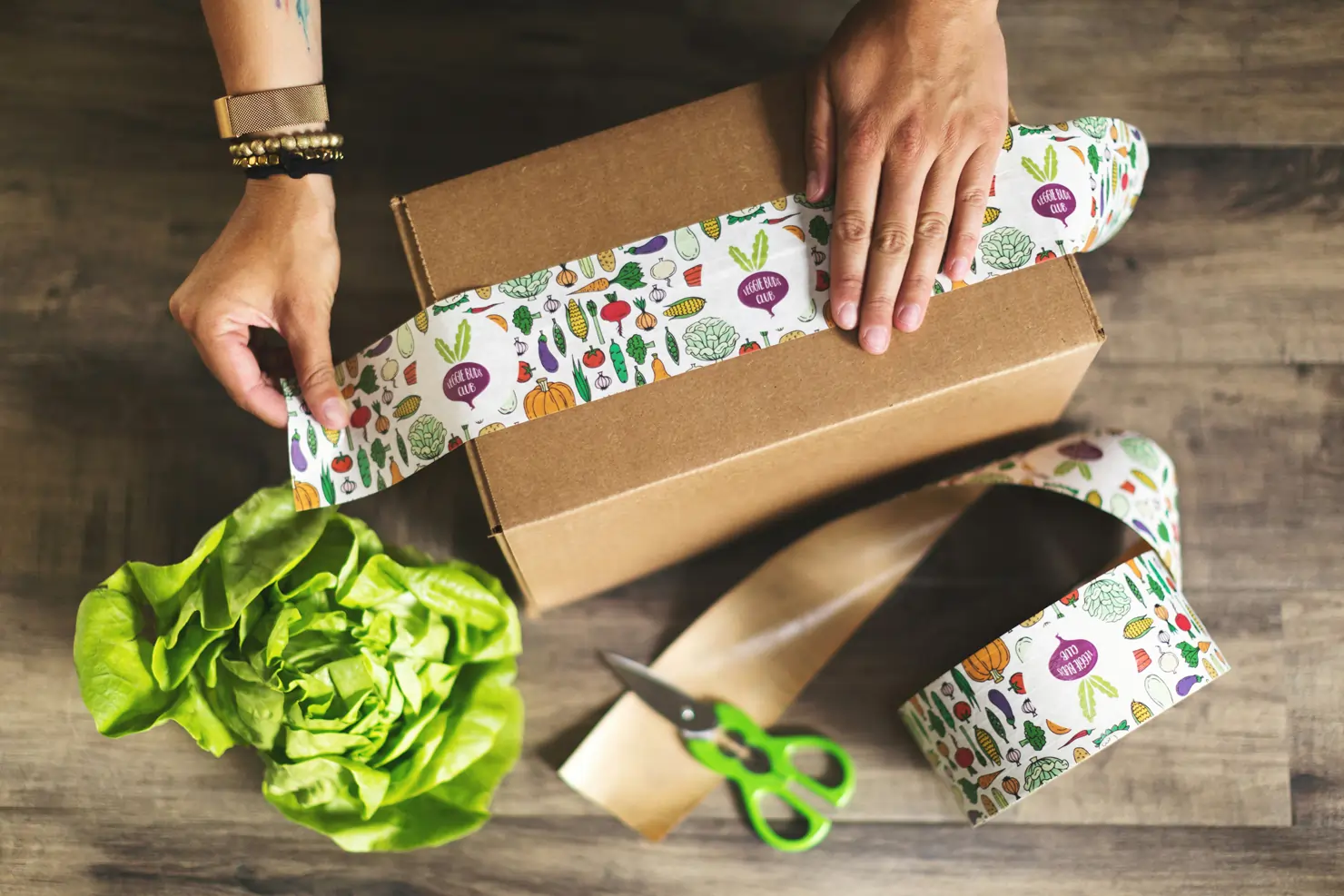 Overhead view of a pair of hands sealing a carton with custom printed packaging tape